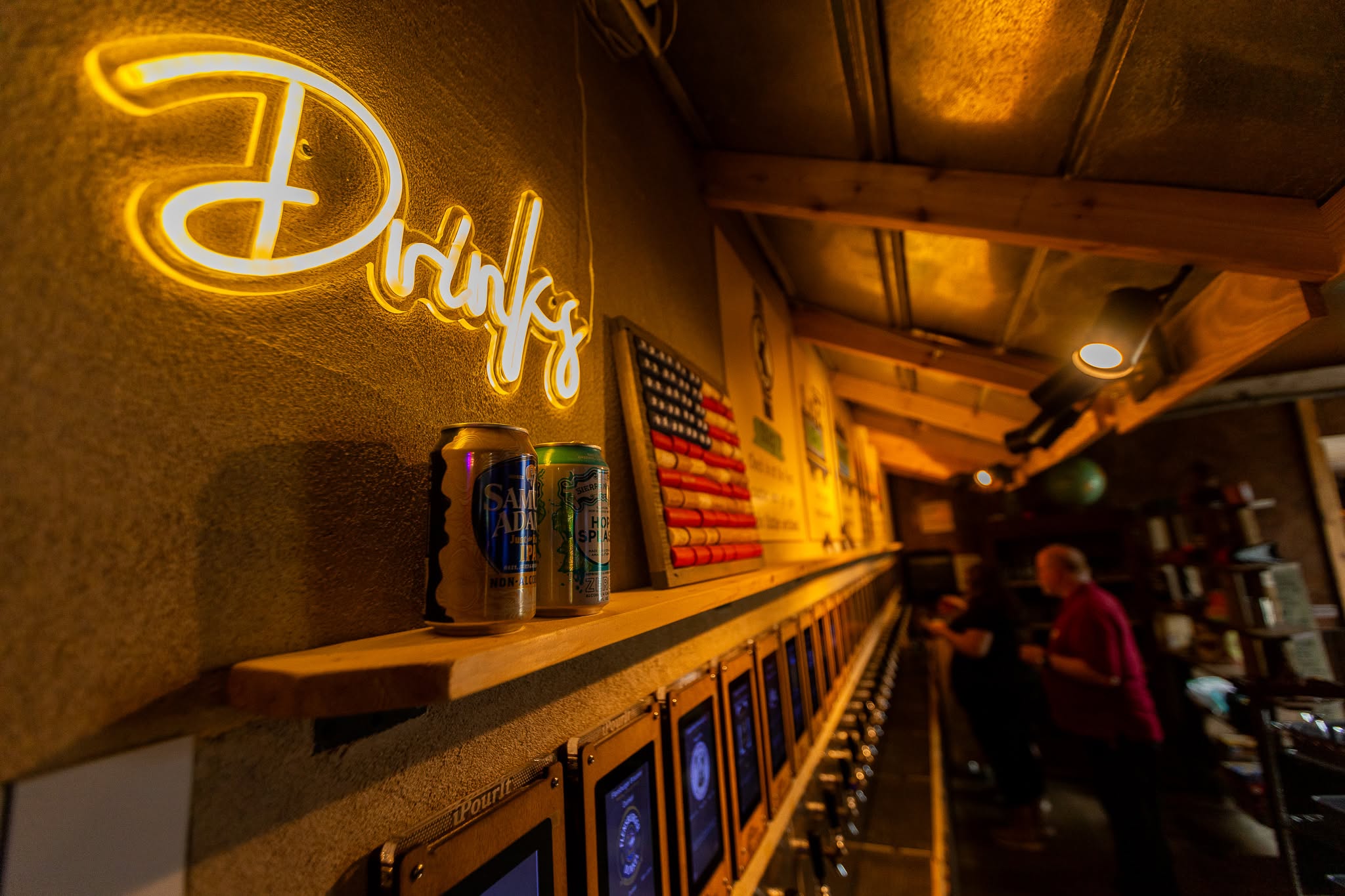 Echo Station's self-pour tap wall under a neon Drinks sign, photographed on location
