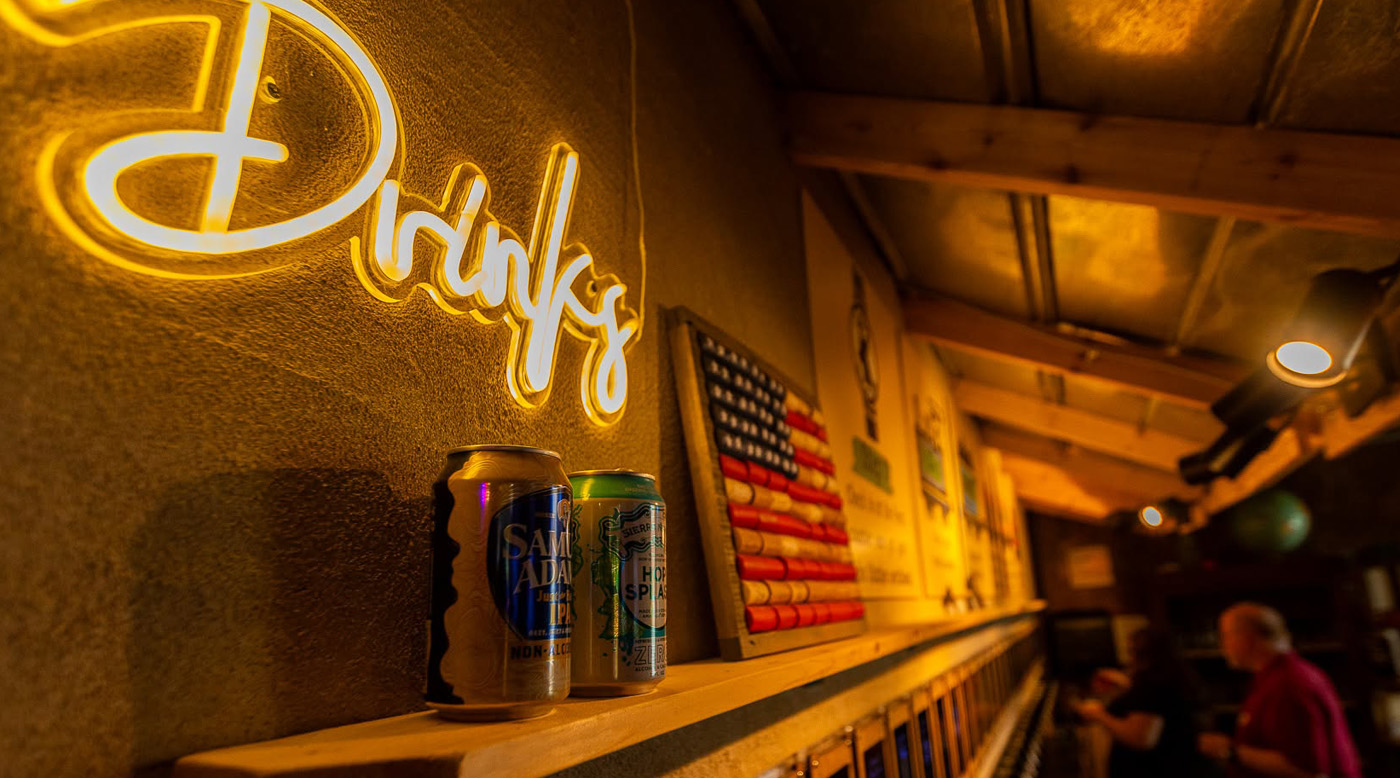 The bar at Echo Station, lit by a neon Drinks sign